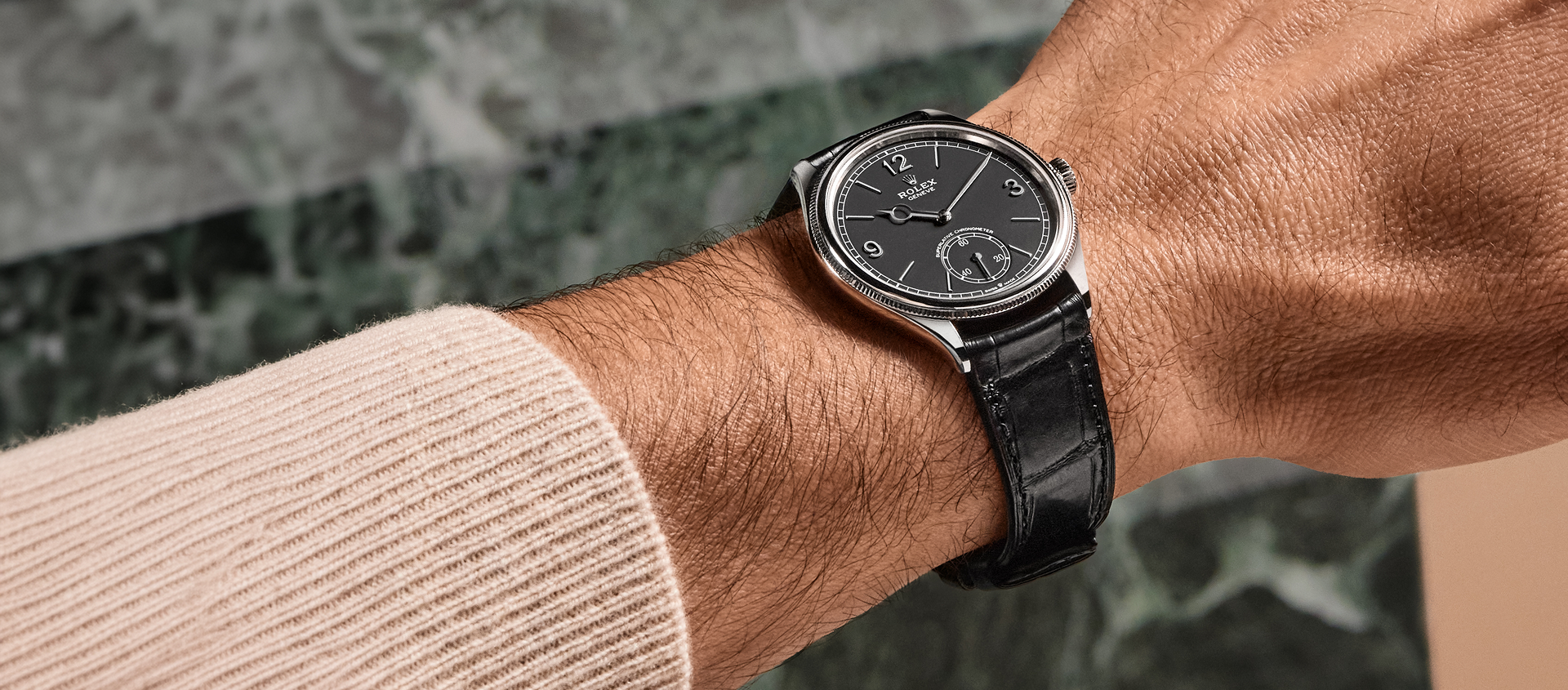 Rolex Perpetual 1908 in white gold with intense black dial worn on wrist against green marble background