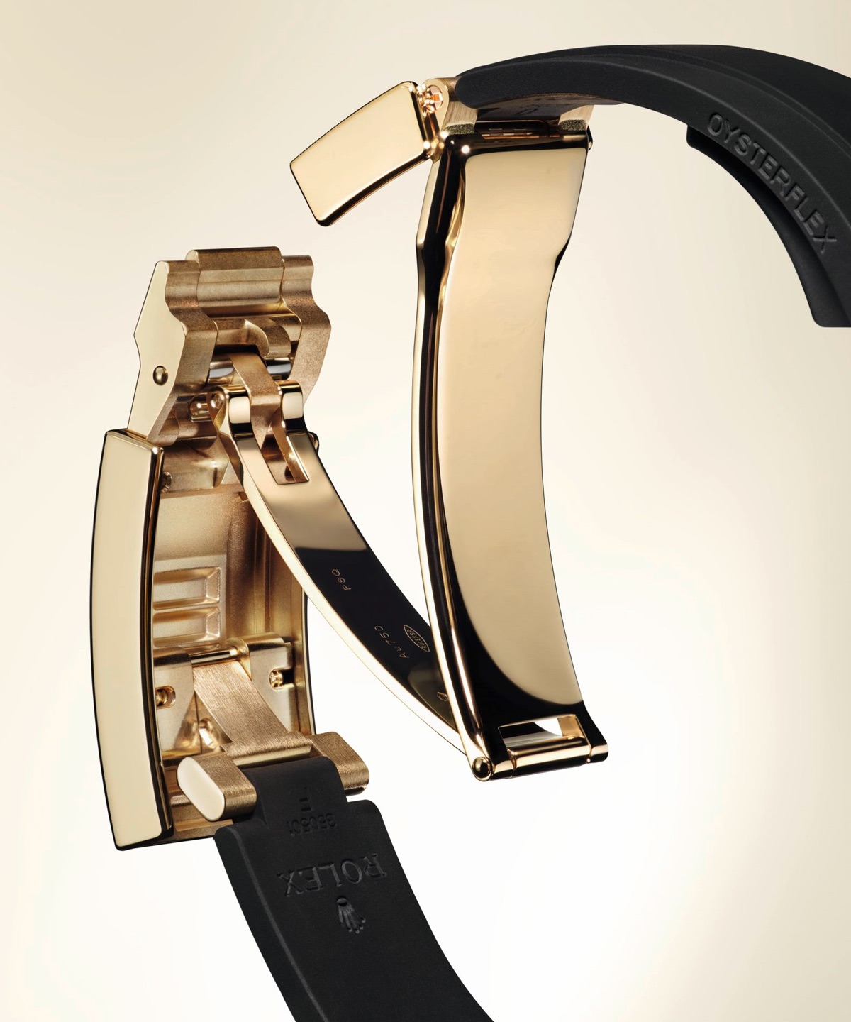 Close-up of the Rolex Oysterflex bracelet in yellow gold showing the Oysterlock safety clasp and Glidelock extension system on a black elastomer strap