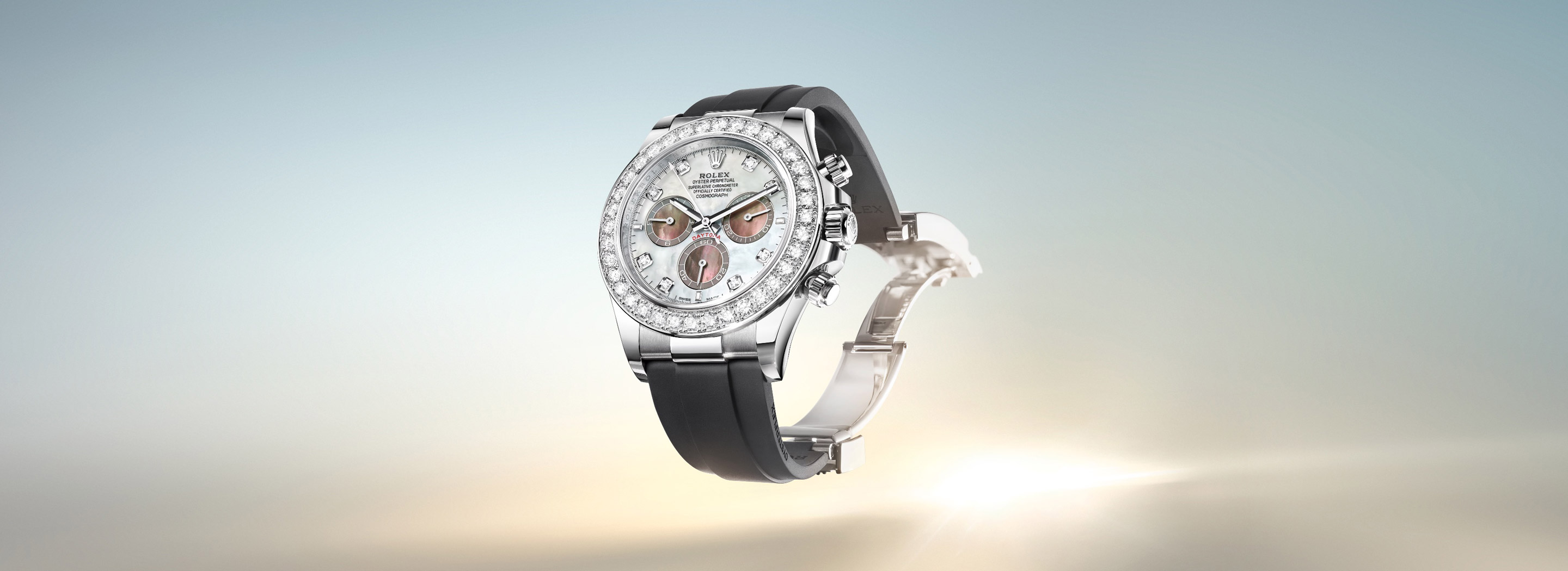 Rolex Cosmograph Daytona in white gold with mother-of-pearl dial and diamond-set bezel on a black Oysterflex bracelet, floating against a sky and horizon background