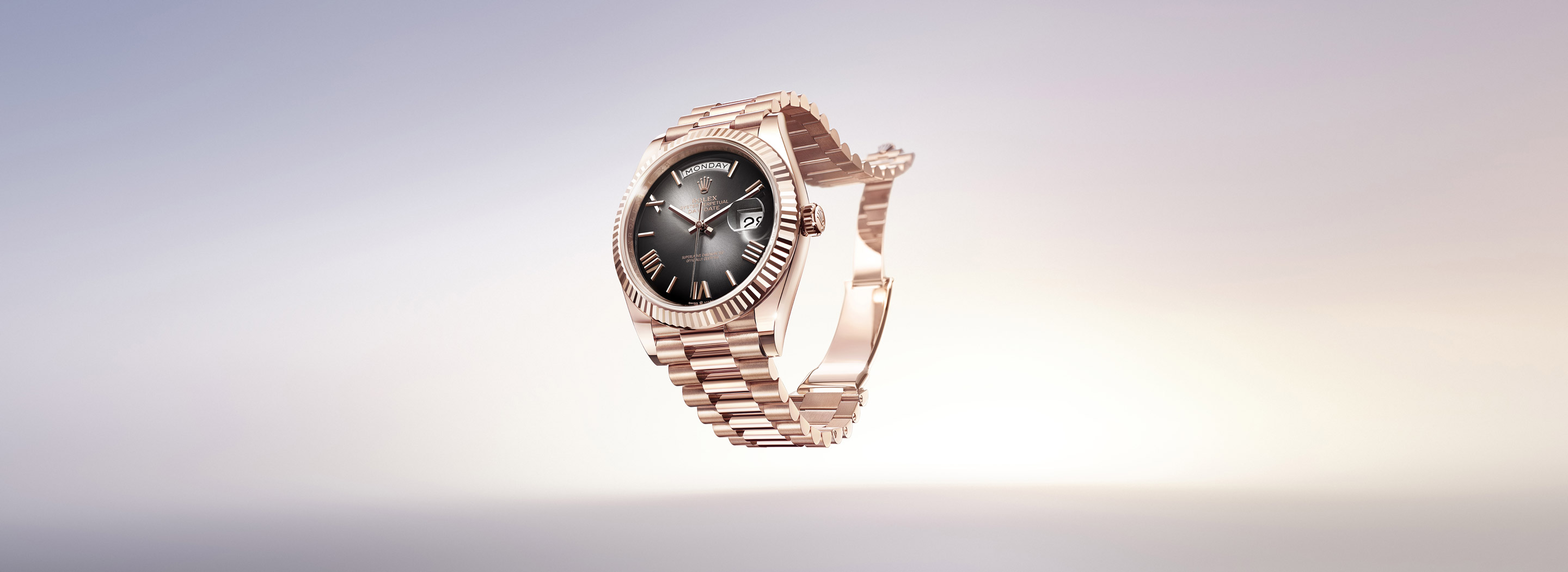 Rolex Day-Date 36 in white gold with pink dial and baguette diamond hour markers on a President bracelet, with multilingual day display reflected beneath