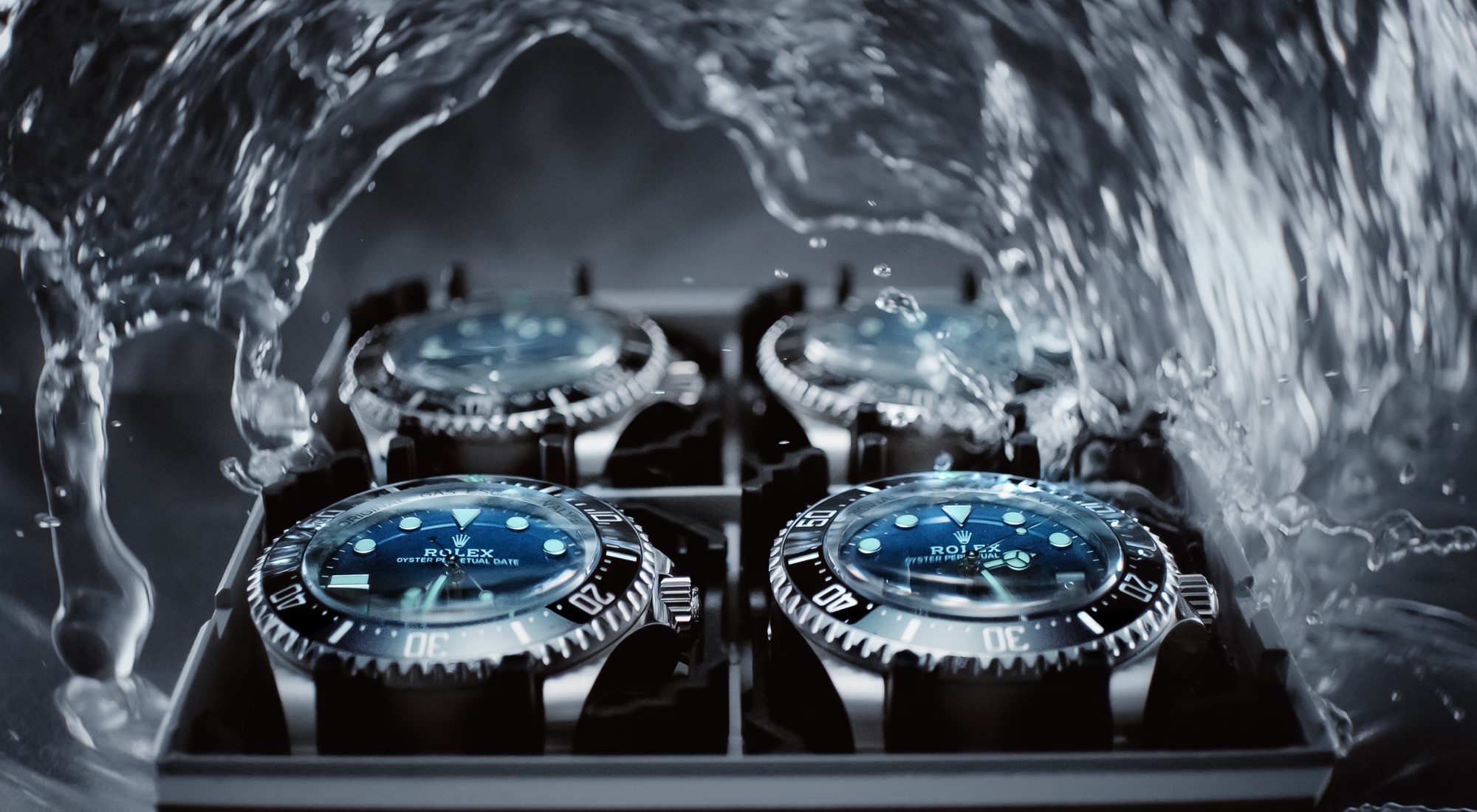 Multiple Rolex Deepsea watches mounted in a testing rack inside a hyperbaric pressure chamber, submerged in water with jets of water flowing around them during stringent waterproofness testing