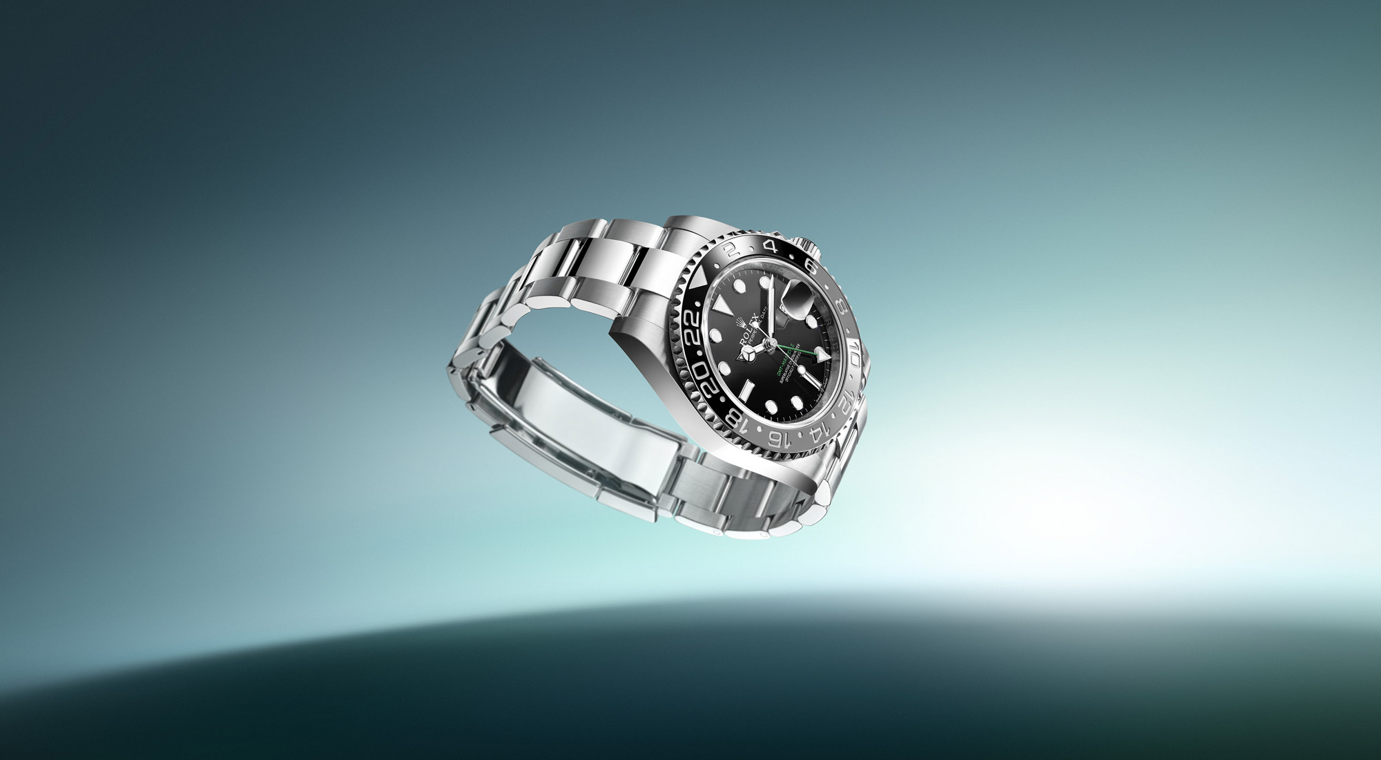 Rolex GMT-Master II in Oystersteel with black dial and green-black Cerachrom bezel on an Oyster bracelet, floating against a teal gradient above a curved horizon