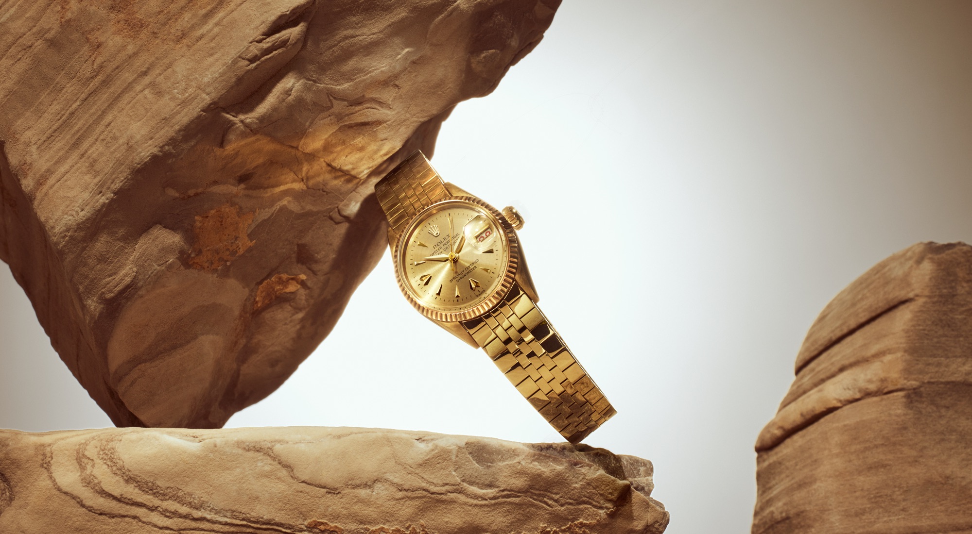 Vintage 1957 Rolex Lady-Datejust in yellow gold with champagne sunray dial and fluted bezel on a Jubilee bracelet, balanced between sandstone rock formations