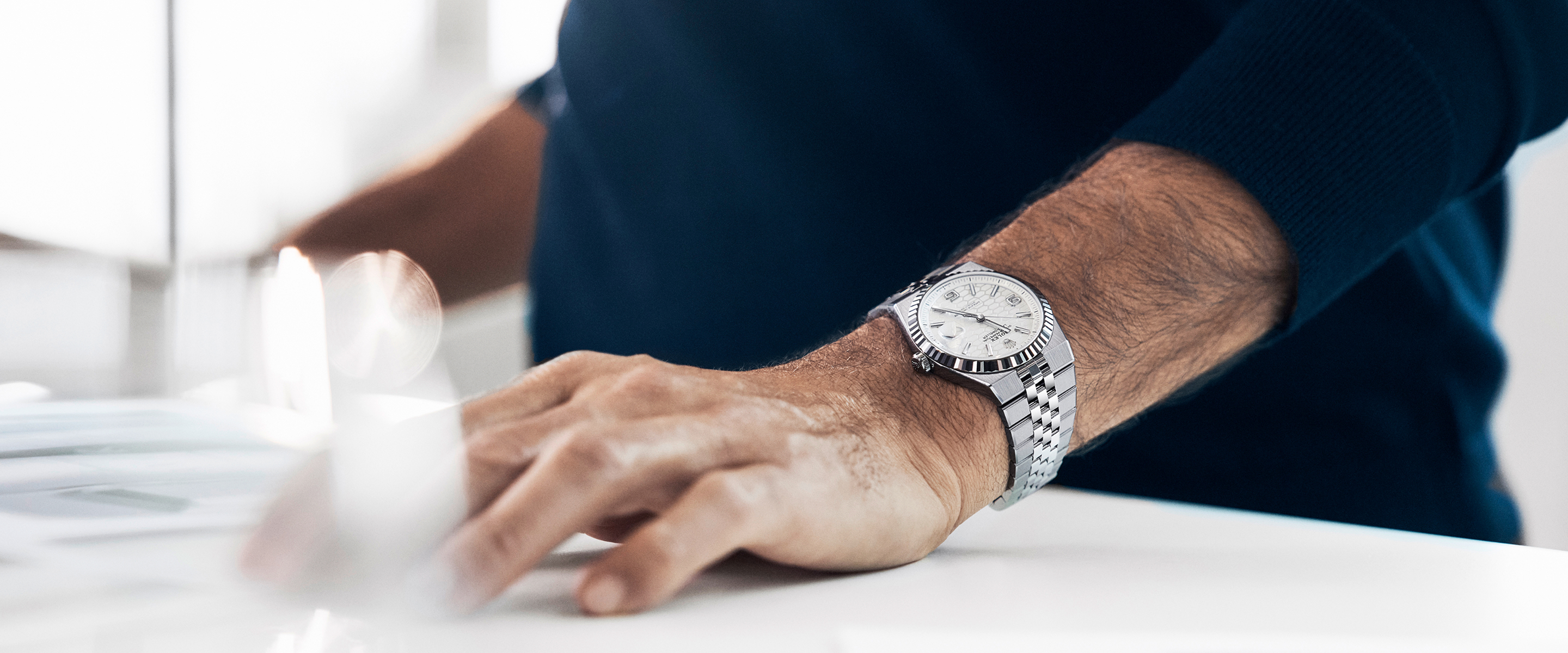Roger Federer wearing the Rolex Land-Dweller on his wrist at a desk