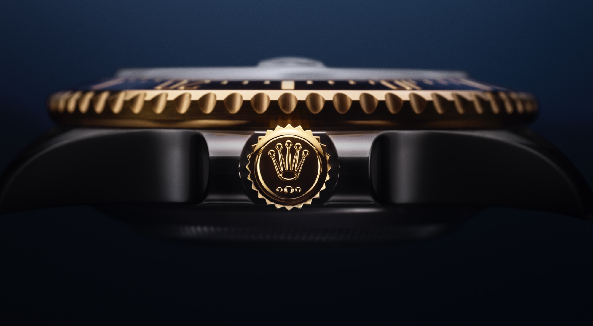 Close-up side profile of the Rolex Sea-Dweller in Oystersteel and yellow gold Rolesor, showing the Triplock winding crown with yellow gold Rolex crown emblem screwed down against the case, and the fluted black Cerachrom bezel above