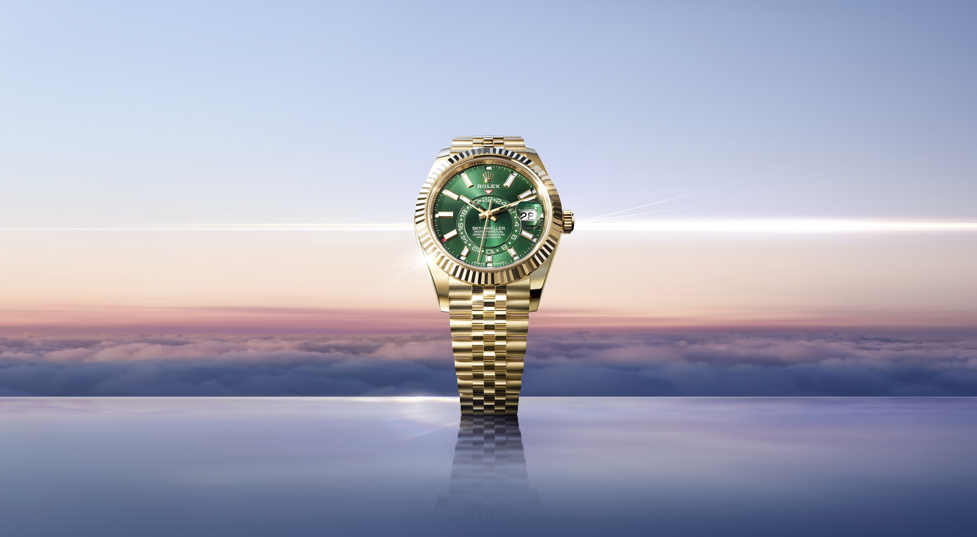Rolex Sky-Dweller in yellow gold with green dial on an Oyster bracelet, set against a coastal landscape at dusk
