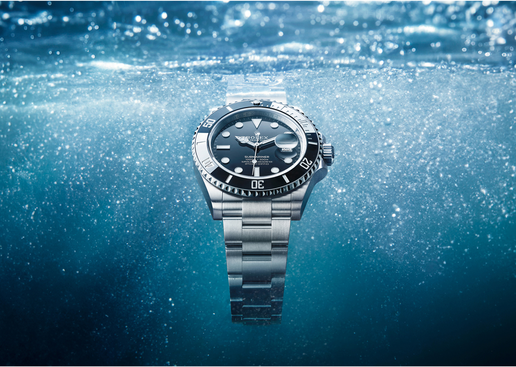 Rolex Submariner Date in Oystersteel with black dial and black Cerachrom bezel on an Oyster bracelet, fully submerged underwater with light filtering through the surface above