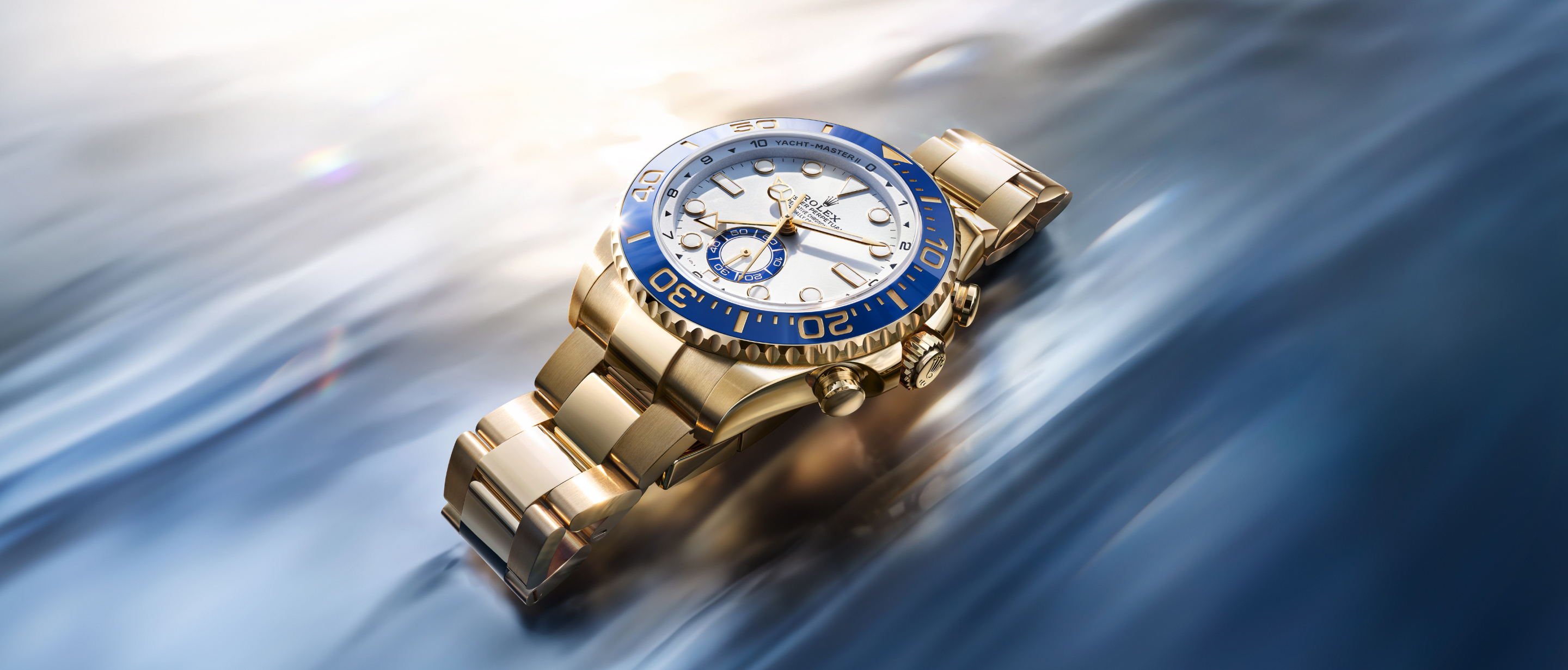 Rolex Yacht-Master II in 18 kt yellow gold with blue Cerachrom bezel gliding across water at speed