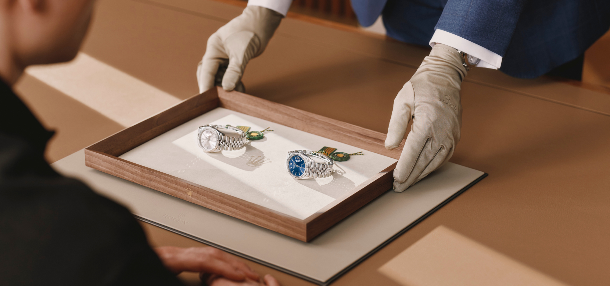 Rolex watch being shown to a woman by a man wearing a cloth glove to protect the appearance of the Rolex timepiece
